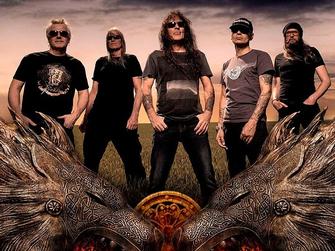 Bild på fem medlemmar i bandet British Lion, med himmel bakom och utsirade varghuvuden framför.