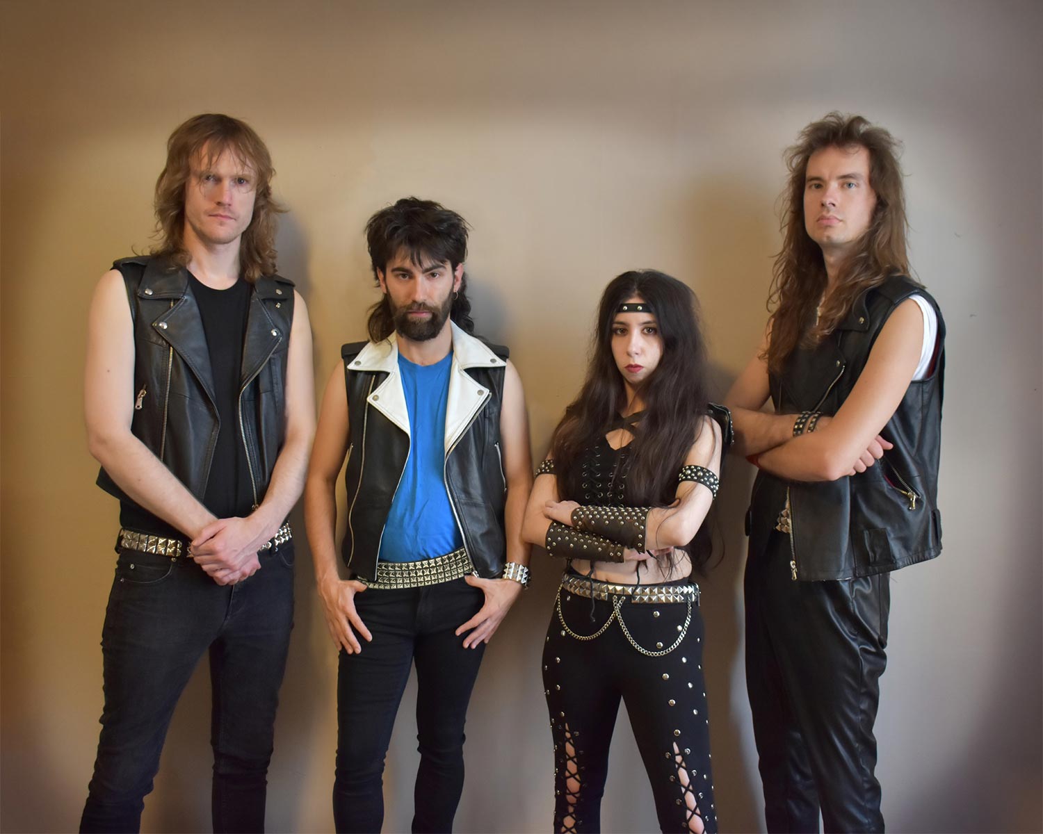 Bronze poserar mot en neutral vägg i klassiska lädervästar och nitbälten.