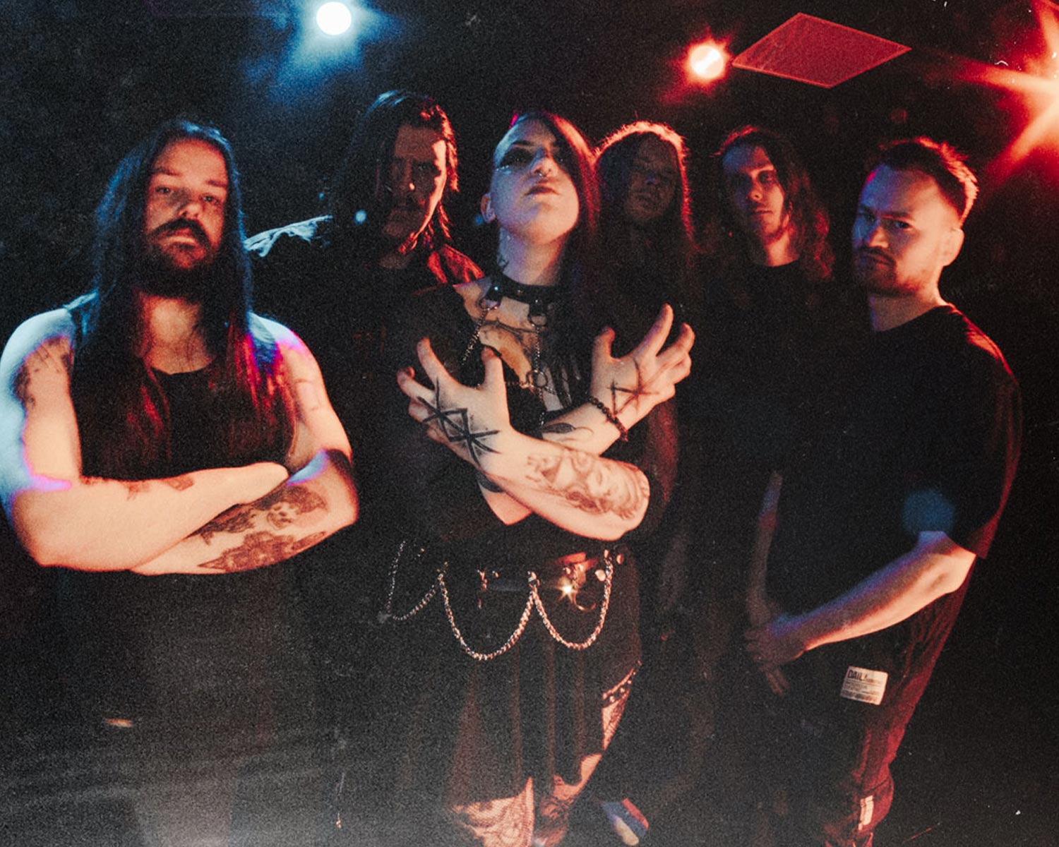 Lysis står samlade i mörk miljö med blå och röda ljus, med intensiv och teatralisk framtoning.