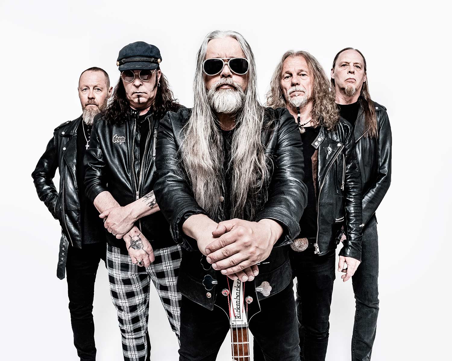 Pressbild av Candlemass: fem bandmedlemmar poserar mot ljus bakgrund. Personen i mitten har långt grått hår, solglasögon och håller en basgitarr framför sig, medan de övriga står bakom i svarta kläder och skinnjackor.