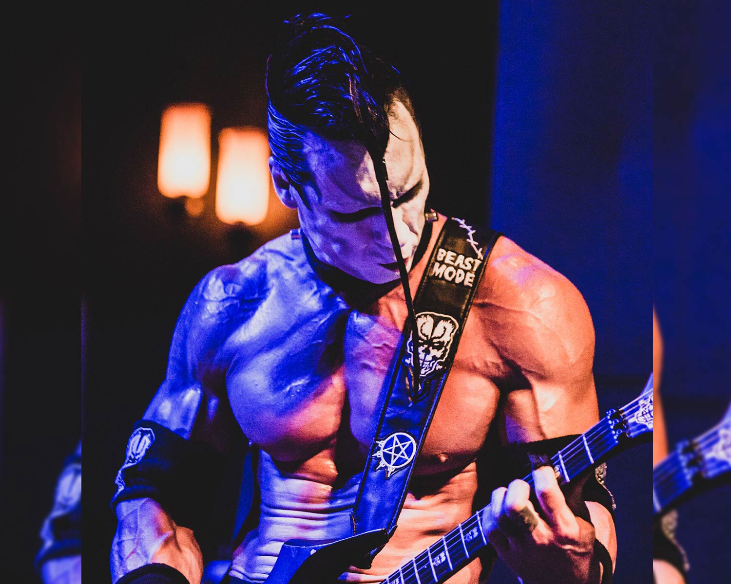 Doyle plays guitar on stage under blue and orange lighting.