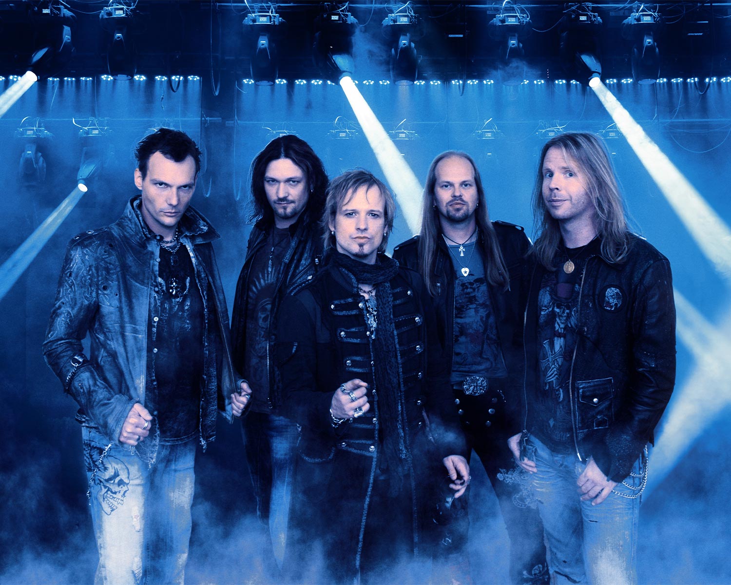 The members of Edguy pose together in a smoky, dimly lit setting.
