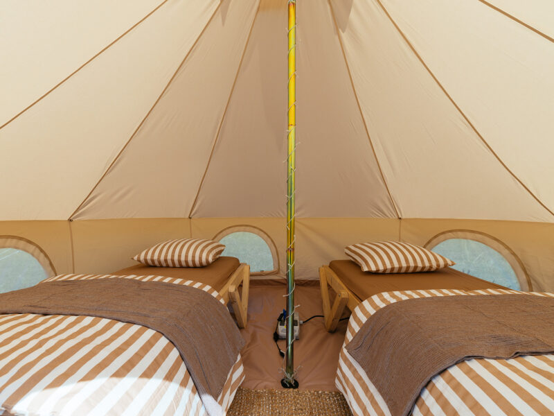 Två bäddar i ett möblerat campingtält.