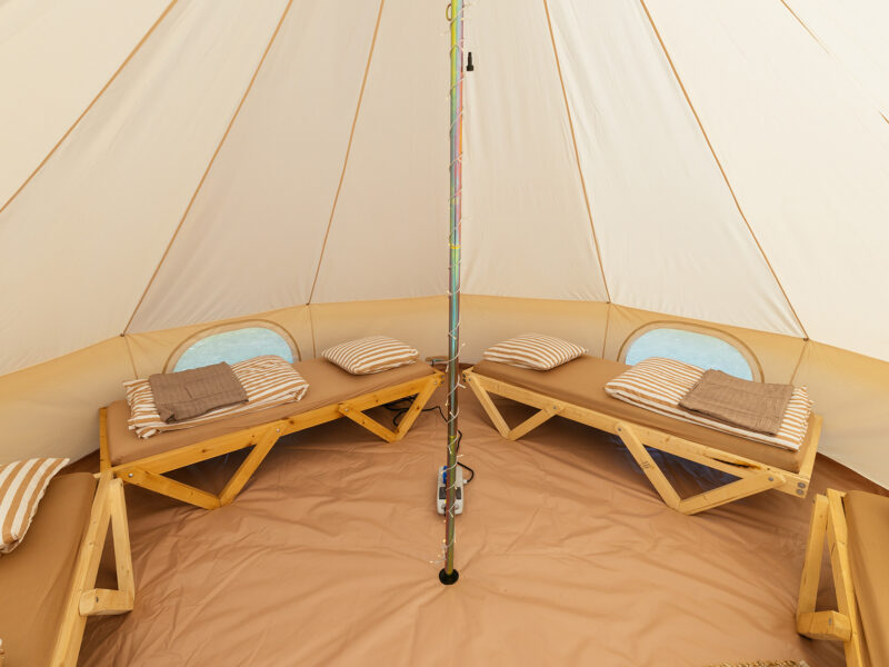 Fyra bäddar placerade längs kanten i ett ljust campingtält på Motorcamp.