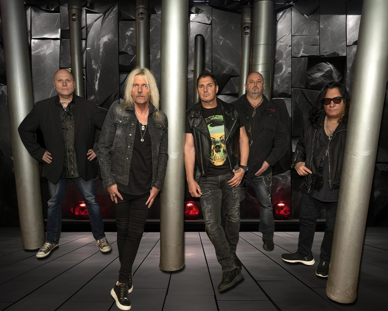 The members of Axel Rudi Pell pose between tall metal pillars in a dark industrial setting.