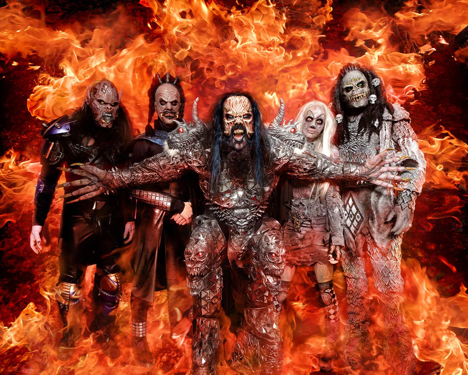 The members of Lordi pose in monster costumes in front of flames.