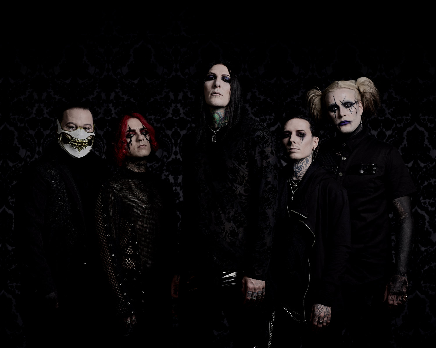 The members of Motionless in White pose in front of a dark, patterned background.