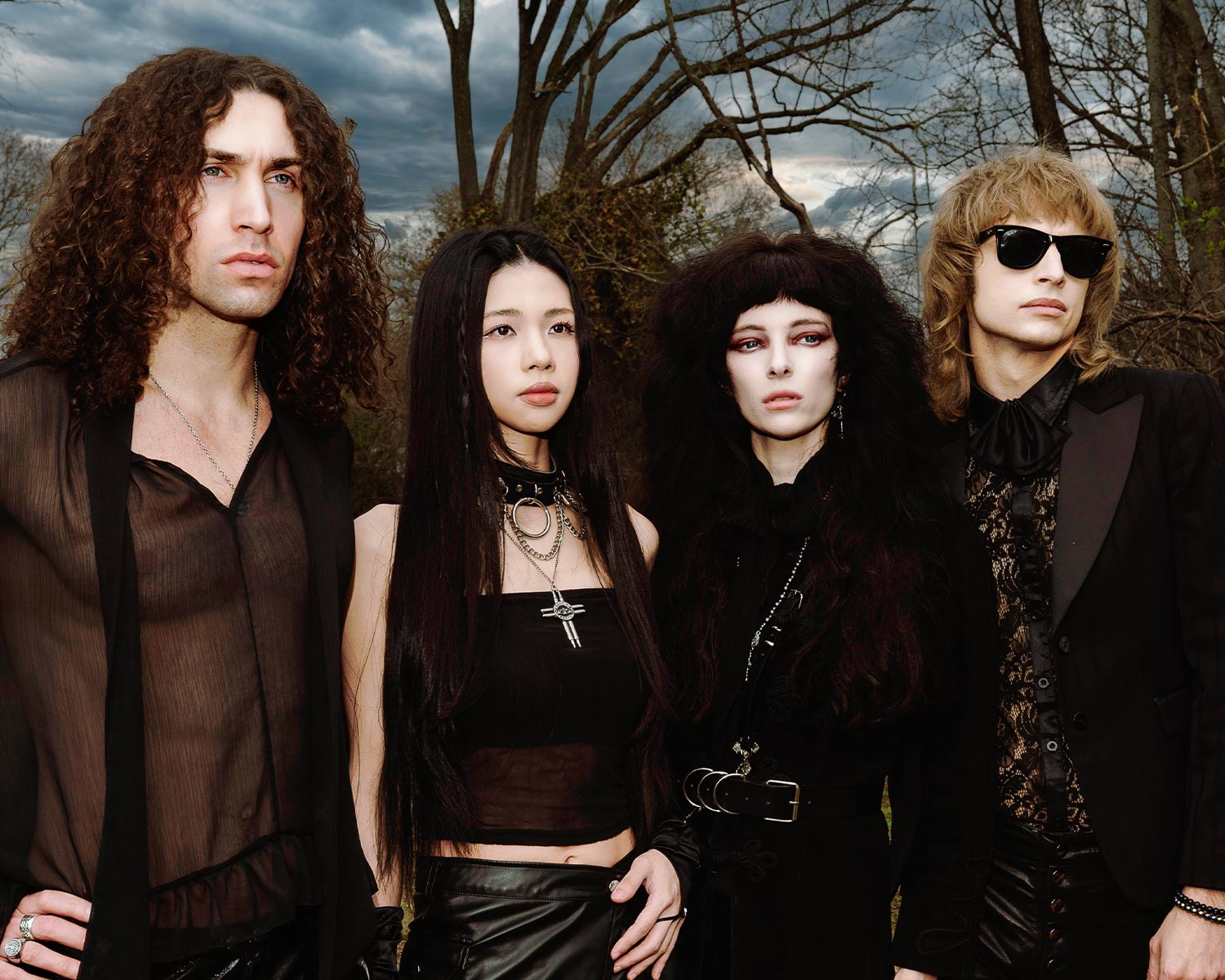 The members of Starbenders are posing outdoors in front of trees and a cloudy sky.