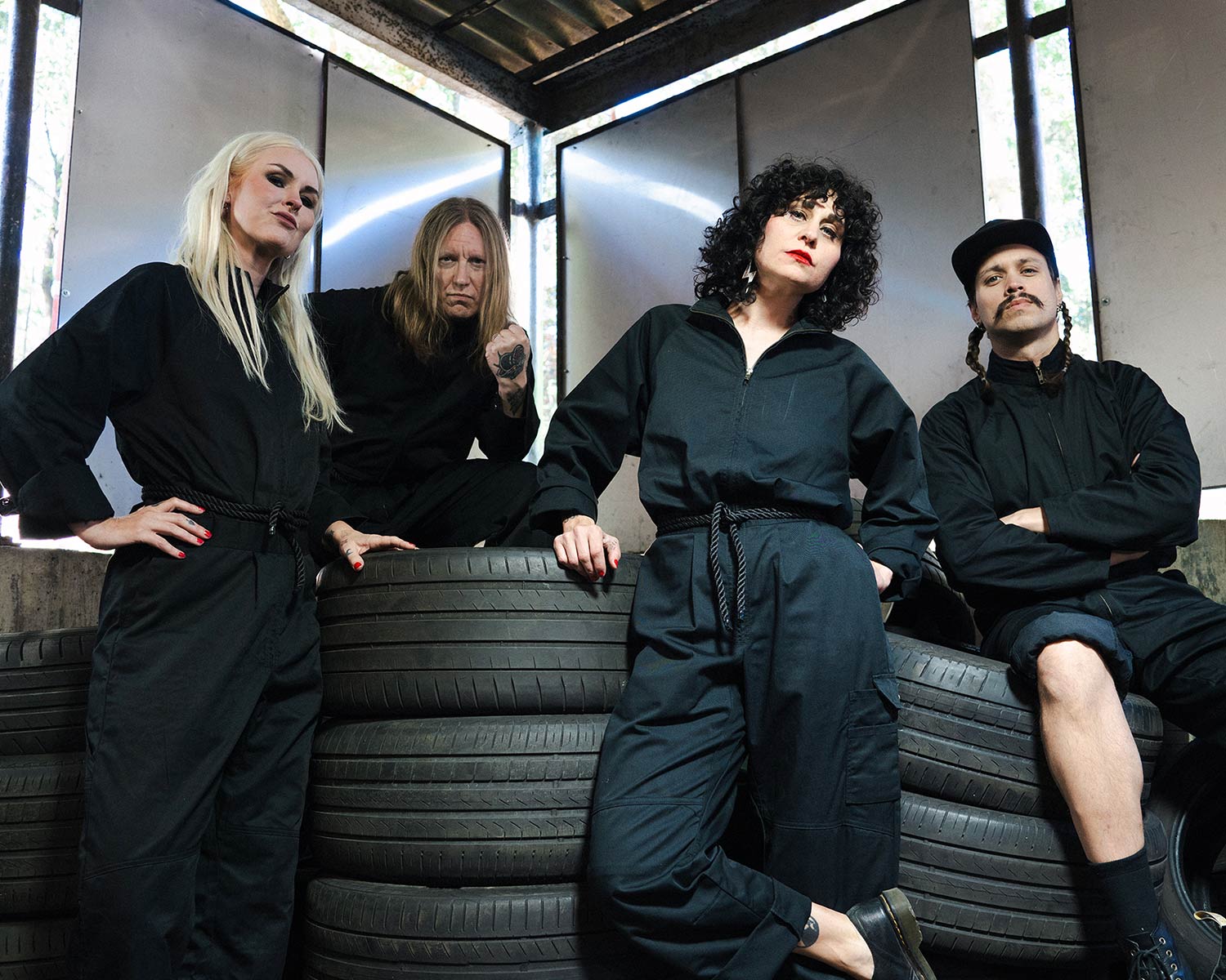 The members of The Baboon Show pose among stacked car tires.