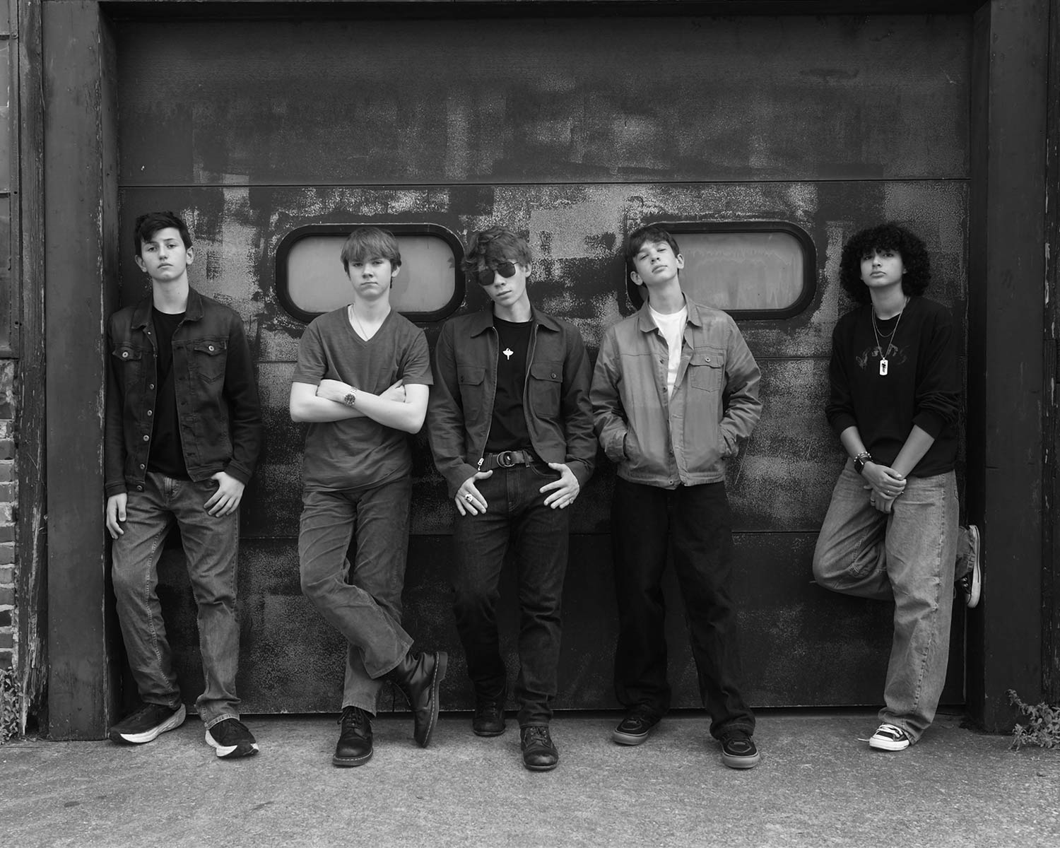 The members of The Photonics pose against an industrial-style wall in black and white.