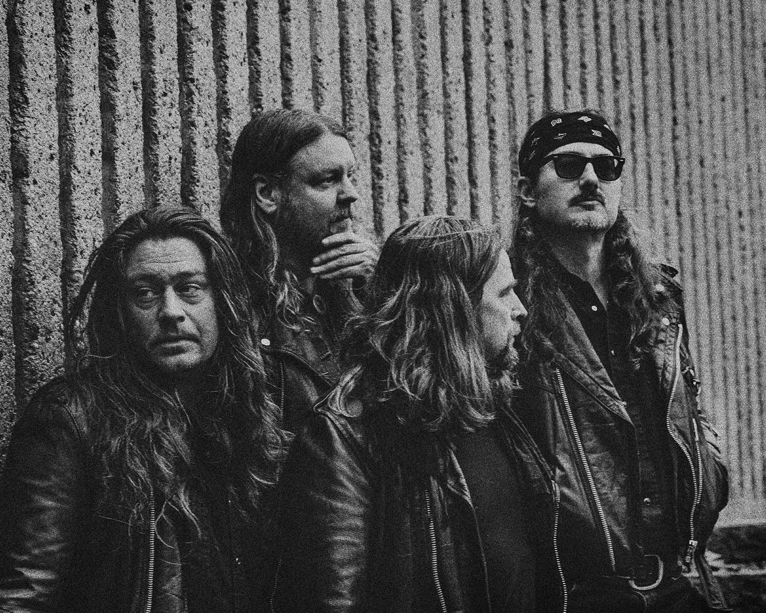 The members of Underground Fire pose against a stone wall in black and white.